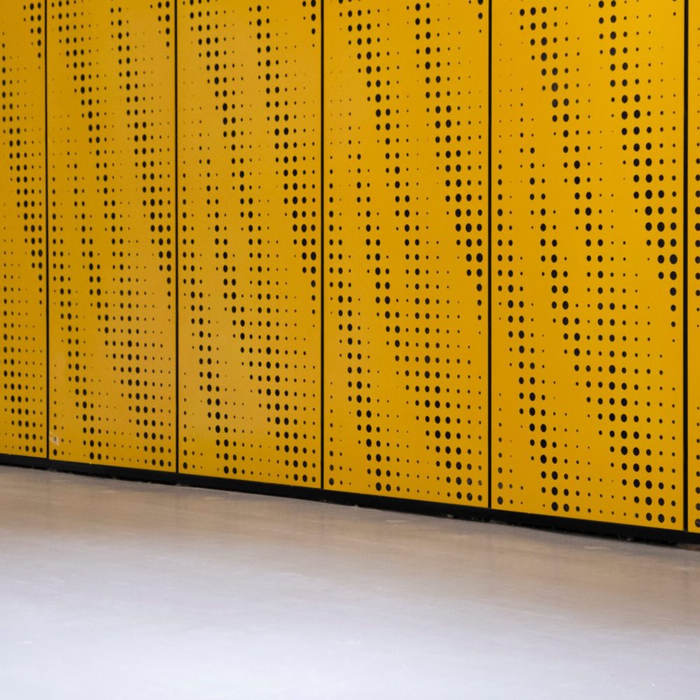 Perforated metal wall background, front view. Yellow metal background with lines and dots.